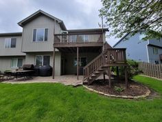 a large house with a deck and grill in the yard next to some lawns