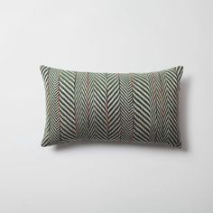 a green and red striped pillow on a white wall with an orange stripe down the middle