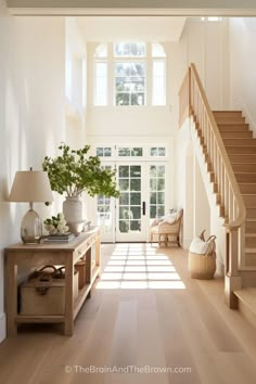 an entryway with stairs and potted plants on the table in front of it