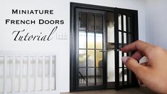 a hand is pointing at the french doors that are open in front of a white wall