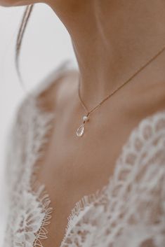 a woman wearing a necklace with a tear drop