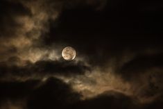 the full moon is seen through some dark clouds