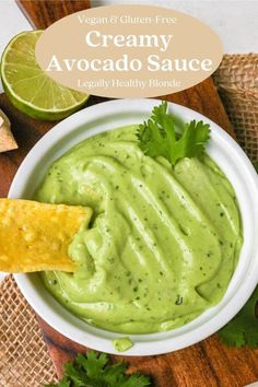 a white bowl filled with creamy avocado sauce and a tortilla chip