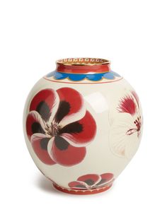 a white vase with red and blue flowers painted on the front, sitting against a white background