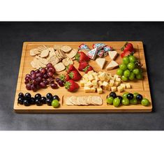 a wooden cutting board topped with grapes, cheese and crackers