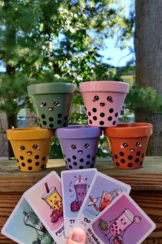 a hand is holding four cards in front of some potted plants