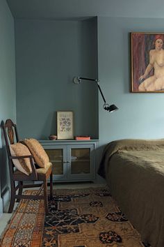 a bed room with a neatly made bed and a painting on the wall