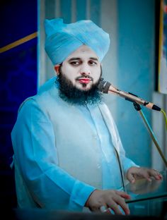 a man with a blue turban is holding a microphone in front of him