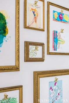 a wall with many paintings on it and some gold frames hanging up against the wall