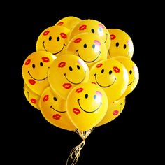 a bunch of smiley face balloons with red lips on them, hanging from a string