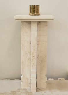 a white marble pedestal with two gold candles on top