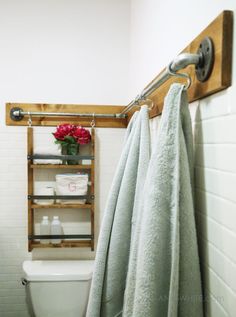 a white toilet sitting in a bathroom next to a wooden shelf with towels on it