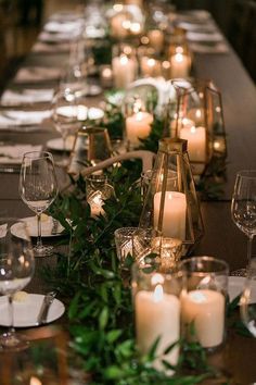 a long table is set with candles and greenery