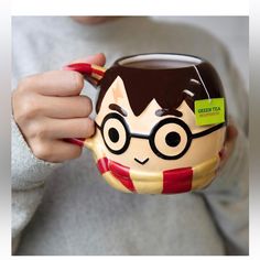 a person holding a harry potter mug with glasses on it's face and mouth