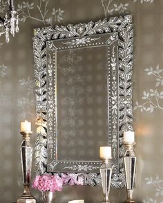 an ornate mirror with candles and flowers in front of it