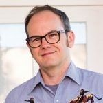 a man wearing glasses holding two bugs in his hands