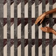 two hands reaching for each other on a marble floor with black and white lines in the background