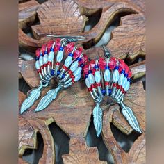 two red, white and blue beaded earrings sitting on top of a wooden table