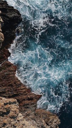 an ocean view with waves crashing on the rocks