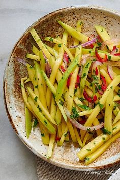 a bowl filled with sliced up vegetables on top of a white table cloth next to a fork