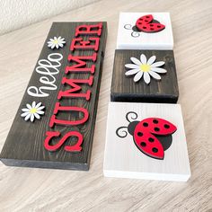 three wooden signs with ladybugs and daisies on them sitting on a table