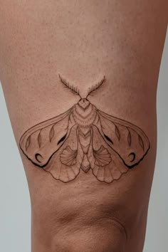 a close up of a person's stomach with a small moth tattoo on it