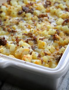 a casserole dish with potatoes and meat in it sitting on a wooden table