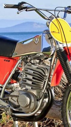 a red dirt bike parked next to the ocean