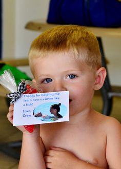 a young boy holding a candy bar with a note attached to it's mouth