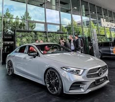 the mercedes benz cla is parked in front of a building with people looking at it