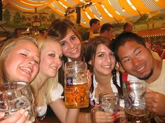 a group of people holding up beer mugs in front of their faces at a bar