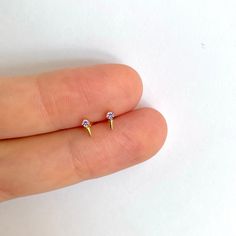 "The tiniest little studs with a tiny spike and a lilac cubic zirconia gemstone for the most understated sparkle. Dainty and minimal, they're perfect for layering with other delicate hoops and studs when you have multiple piercings. ∙ Sold individually (1 stud) or by pair (2 studs) * D E T A I L S * ∙ Material: .925 Sterling Silver or 18K Gold Plated over .925 Sterling Silver ∙ Stone: Lilac cubic zirconia ∙ Dimensions: 5mm x 2mm ∙ Hypoallergenic & nickel-free * P A C K A G I N G * ∙ All jewe Gold Studs Jewelry Gift, Gold Stud Jewelry For Gifts, Gold Studs Jewelry For Gift, Tiny Gold Studs, Amethyst Studs, Stone Studs, Gold Studs, Sterling Silver Earrings Studs, Sterling Earrings