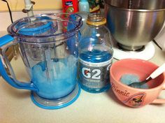 a blender with blue stuff in it next to a bowl and mixer on a counter