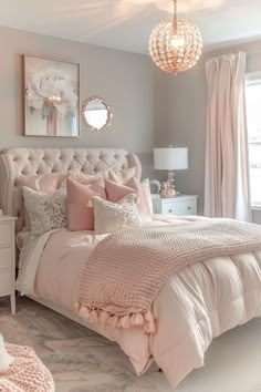 a bedroom decorated in pink and white with a chandelier