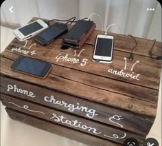 a wooden box with writing on it that says phone charging station and two cell phones