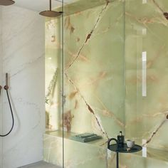 an image of a bathroom with marble walls and flooring in the shower area that has glass partitions