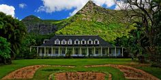 the house is surrounded by lush green trees and mountains in the background, with a heart shaped pathway leading up to it