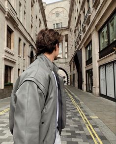 a man is walking down the street wearing a jacket and tie