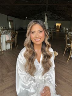 a woman in a white robe sitting on a chair with long hair and wearing a feathered shawl