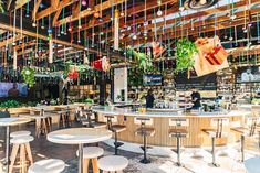 the inside of a restaurant with wooden tables and stools, hanging decorations on the ceiling