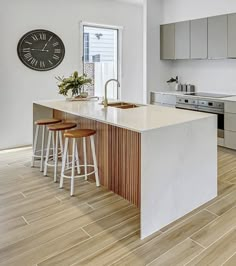 a kitchen with an island counter and stools next to a clock on the wall