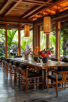 a large wooden table surrounded by black chairs and potted plants on top of it