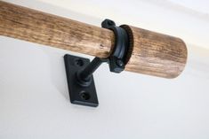 a close up of a wooden handle on a white wall with a black metal hook