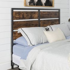 a bed that has some pillows on top of it and a painting above the headboard