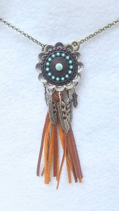 a close up of a necklace with beads and feathers hanging from it's center