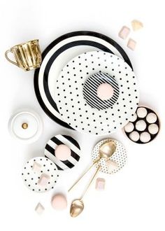 black and white plates with gold spoons, cups and utensils on them