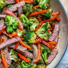 broccoli, carrots and beef in a skillet with sesame seeds on the side