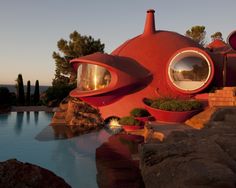 a red house with round windows next to a pool