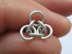 a small silver ring with two intertwined rings on it's side, held in someone's hand