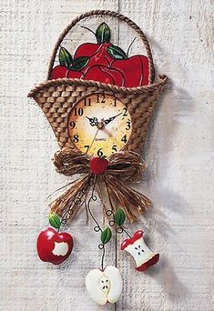 an apple clock hanging from the side of a white wall next to two red apples